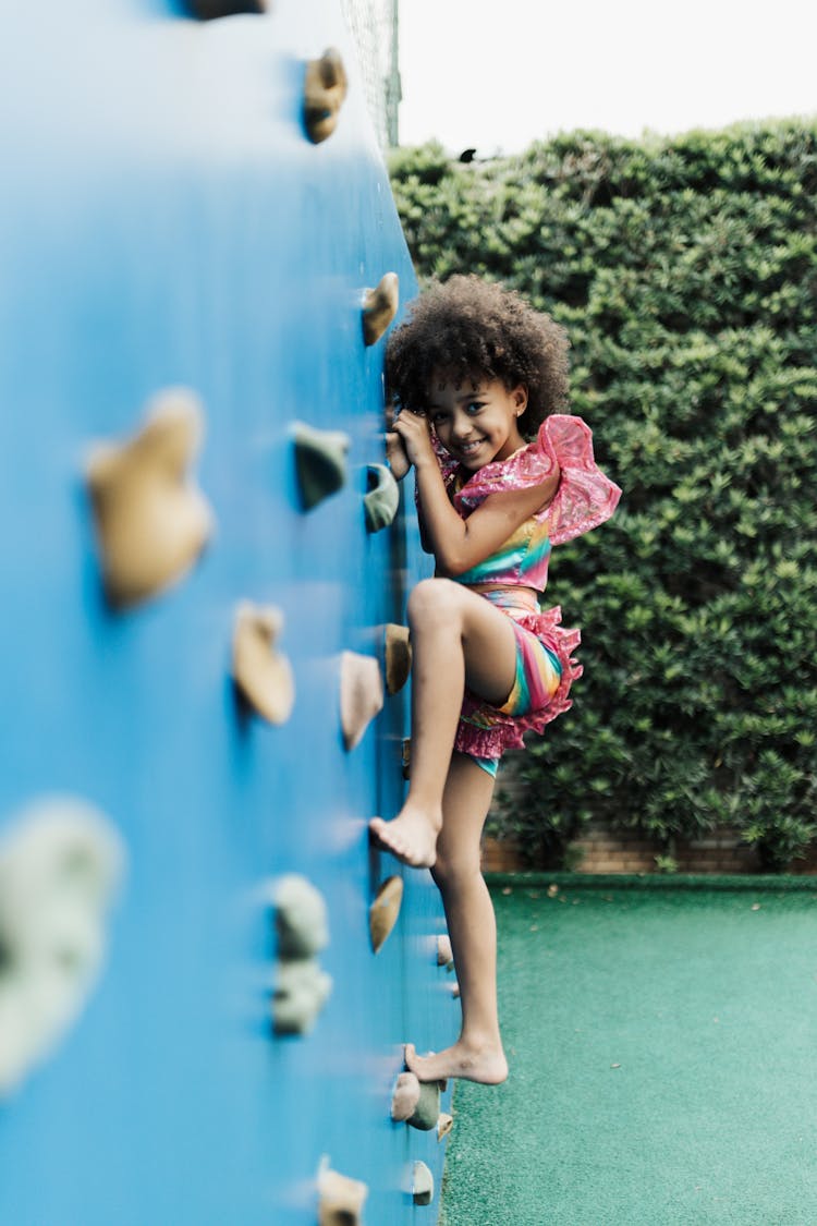 Little Girl Climbing On Wall In Playground