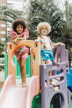 Two children enjoying playtime on a vibrant playground slide.