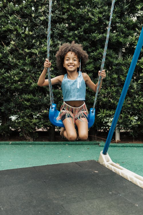 Free A Little Girl on a Playground Swinging and Smiling  Stock Photo