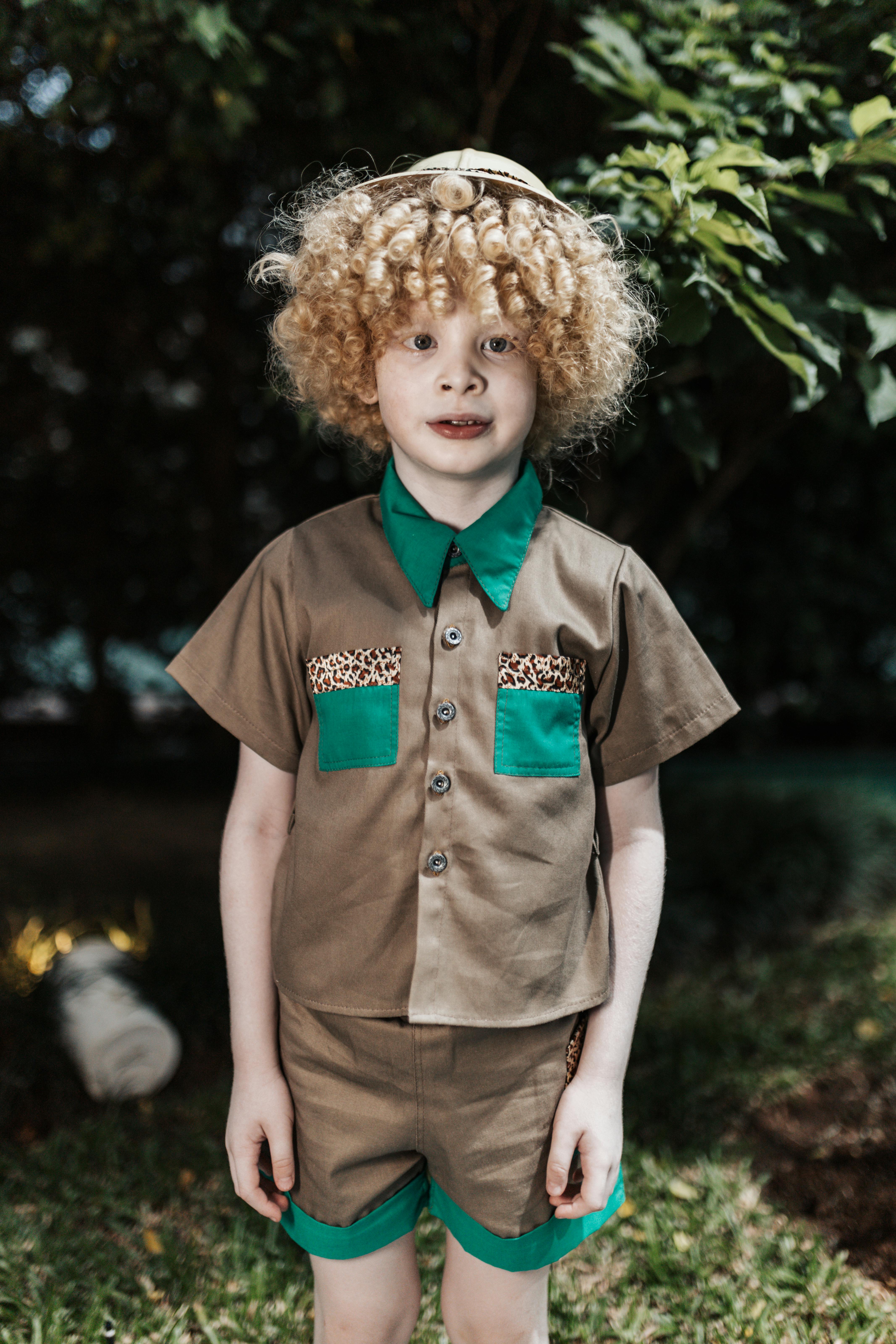 a little boy with curly hair standing outside