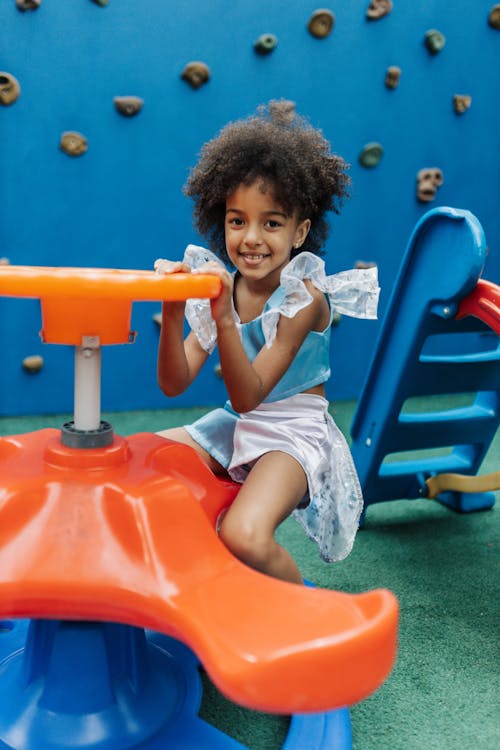 Curly Girl Sitting on a Plastic Carousel