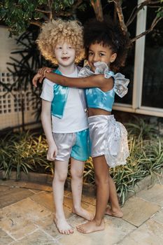 Two children happily hugging in colorful costumes, showcasing friendship and joy.