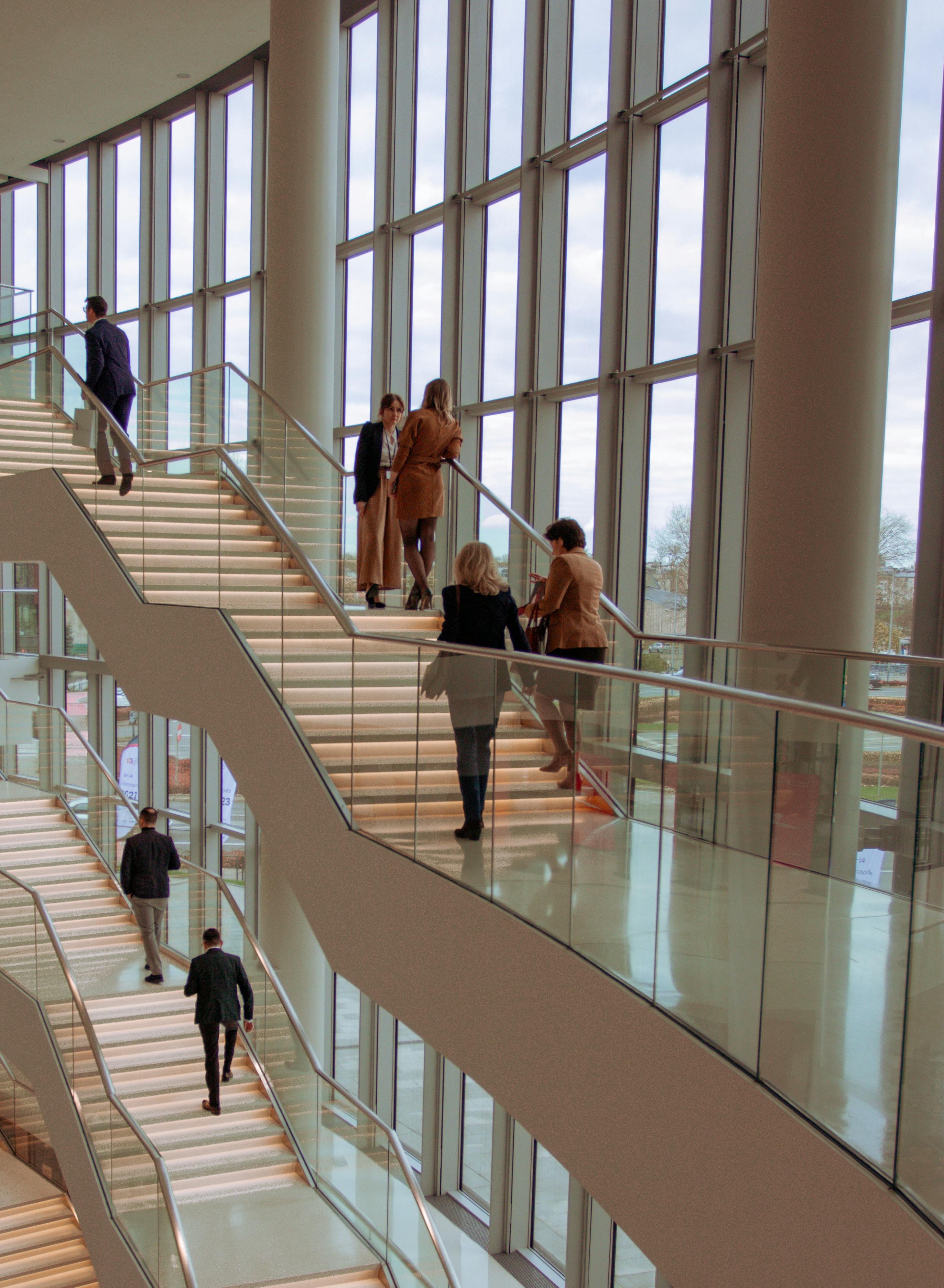 Individuals on a contemporary staircase in a modern building, captured indoors with bright natural lighting.
