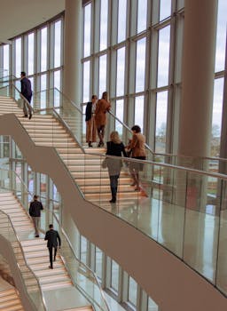 Individuals on a contemporary staircase in a modern building, captured indoors with bright natural lighting.