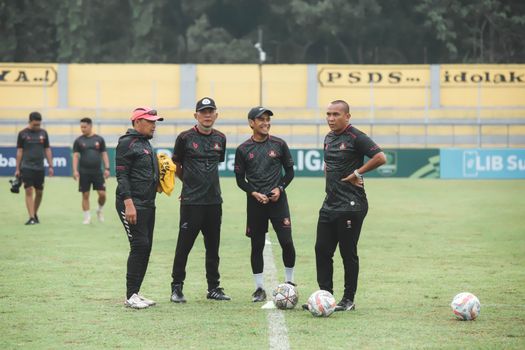 Group of Indonesian coaches discussing on the soccer field during daytime.