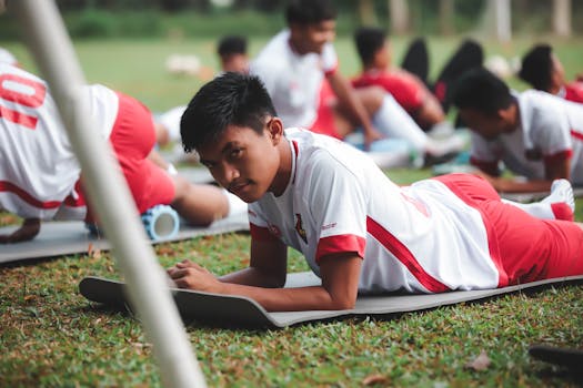 Young soccer players participating in outdoor training laying on exercise mats.