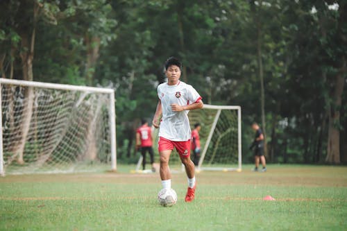 A young man in red and white soccer uniform kicking a soccer ball