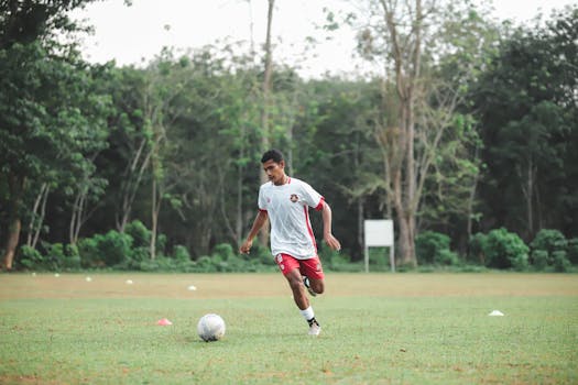 A young soccer player dribbling a ball on a grassy field during daytime practice.