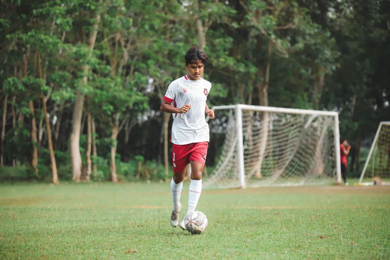 Young player in red and white striking the ball