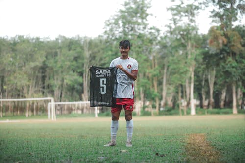 A man holding a soccer jersey in the grass