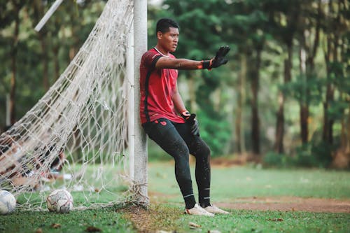 A young man is sitting on the ground near a goal