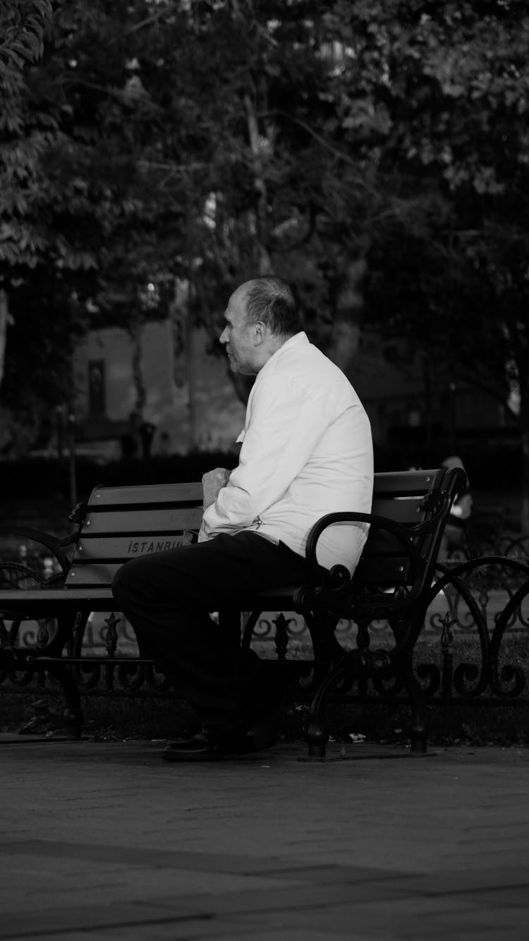 Elderly Hunched Man Sitting On A Bench