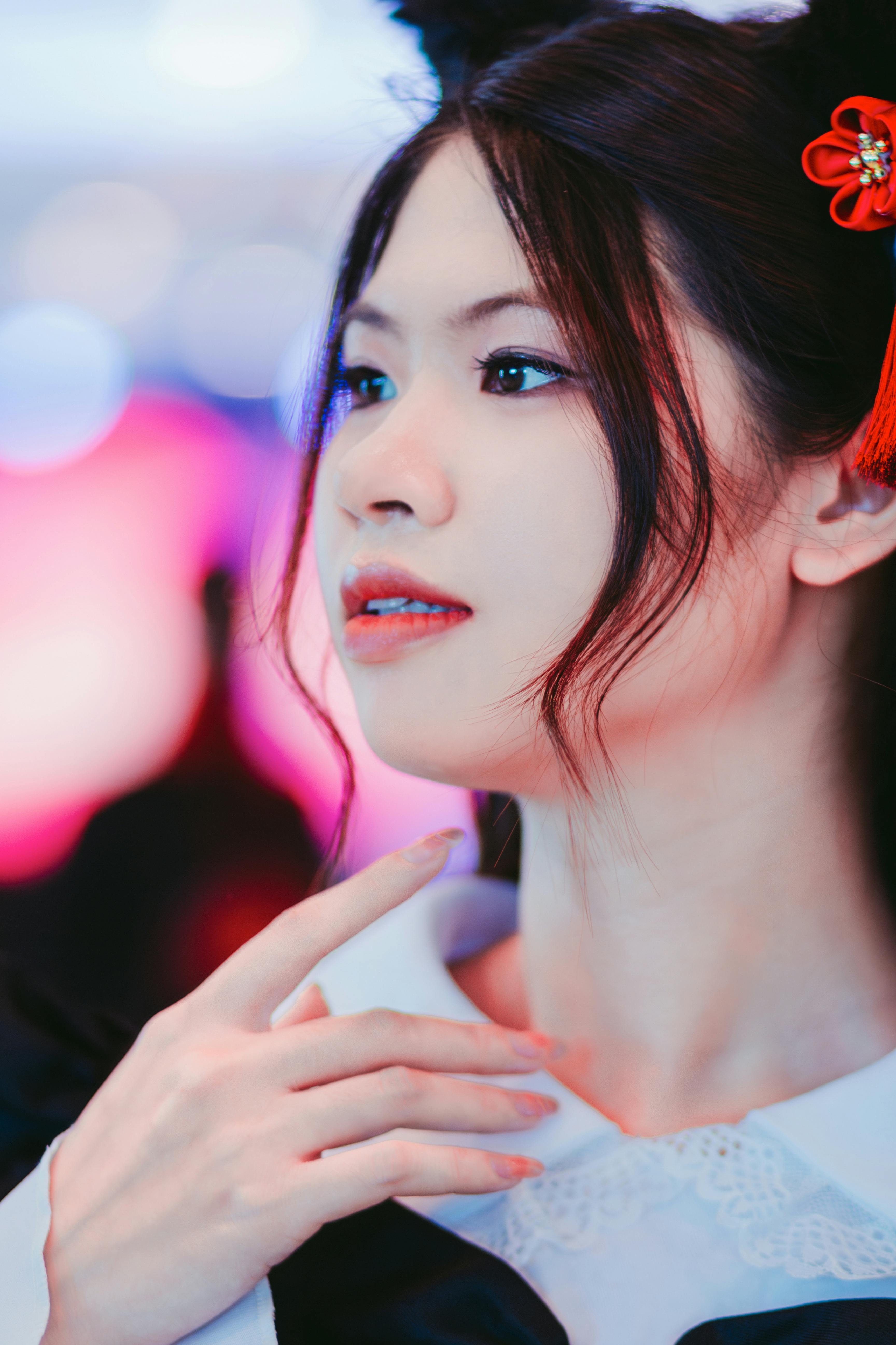 Close-up portrait of an East Asian woman with vibrant background and delicate features.