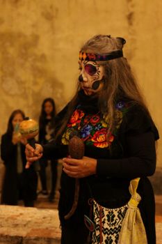 Woman in traditional attire during Day of the Dead ceremony with face paint and maracas. — photo by Anya  Juárez Tenorio