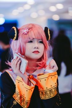 Vivid portrait of an adult in anime cosplay with pink wig and costume indoors.