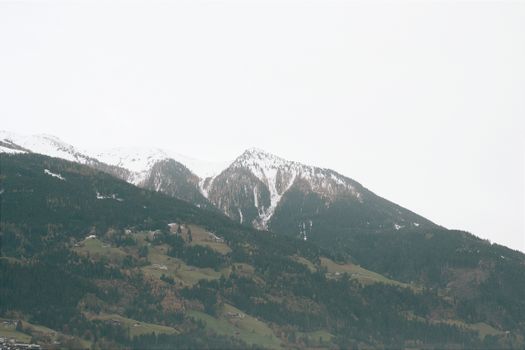 Scenic view of snow-capped mountains in Tyrol, Austria with lush green terrain.