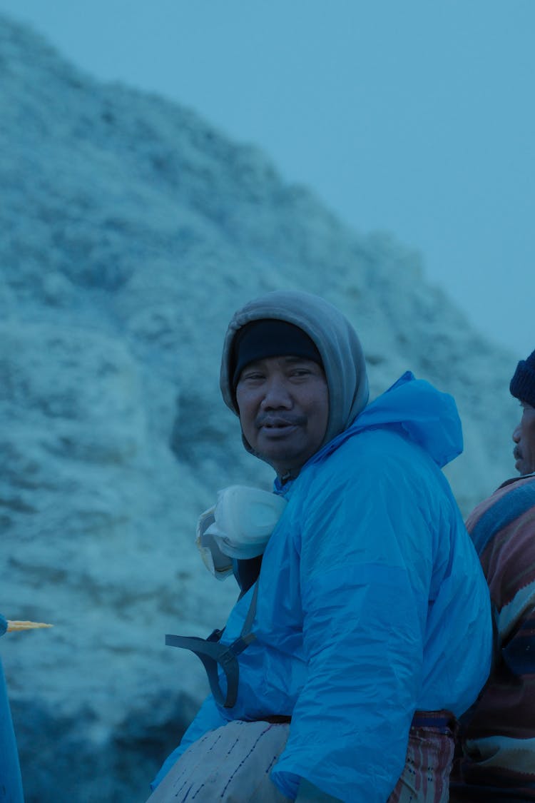 Portrait Of A Man In Hooded Sweatshirt, Beanie Hat, And Blue Protective Overalls