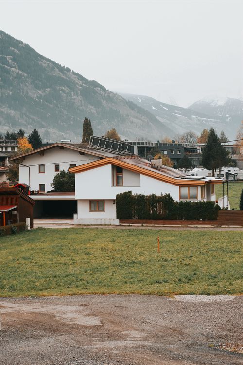 Free Experience the serene landscape of a Tyrolean village with modern architecture set against majestic mountains. Stock Photo