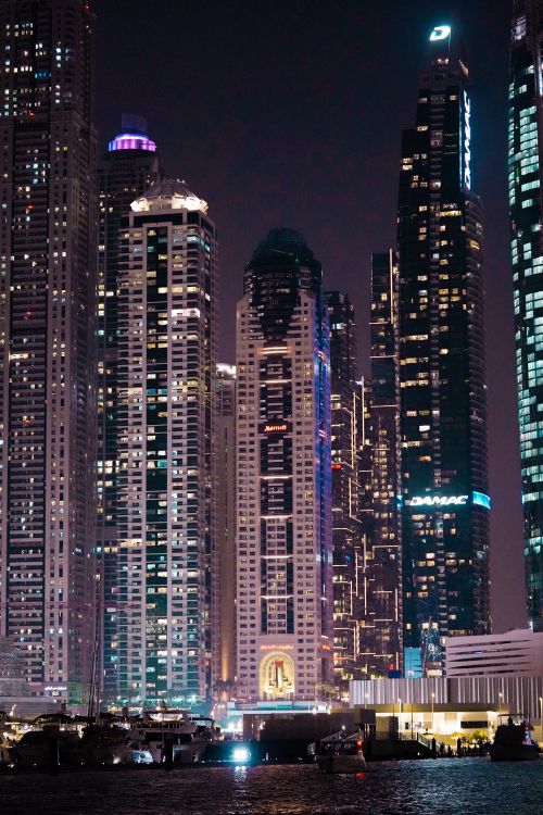 Free Captivating Dubai skyline with illuminated skyscrapers reflecting in water at night. Stock Photo