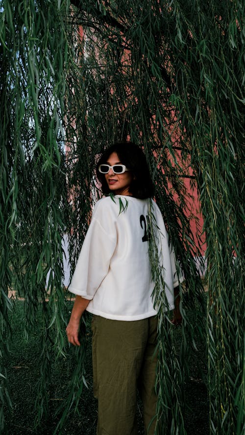 https://images.pexels.com/photos/19232493/pexels-photo-19232493/free-photo-of-model-in-white-loose-sweatshirt-with-print-and-olive-pants-among-willow-branches.jpeg?auto=compress&cs=tinysrgb&dpr=1&w=500