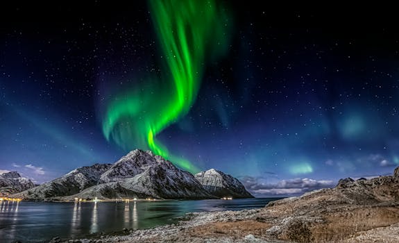 Captivating view of the aurora borealis illuminating the winter night sky over Flakstad mountains, Norway.