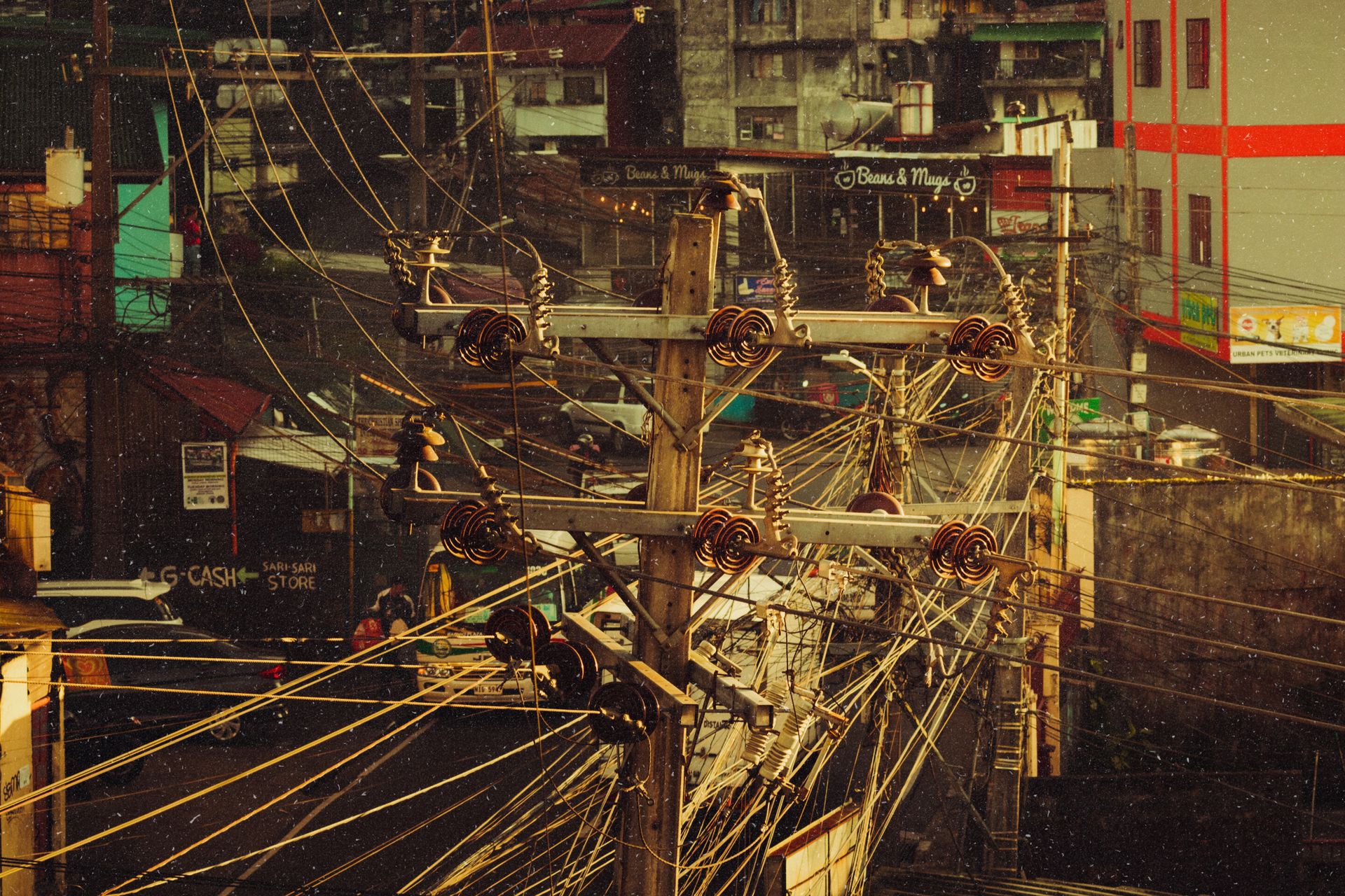 A busy urban scene with a network of tangled power lines and buildings in the background.