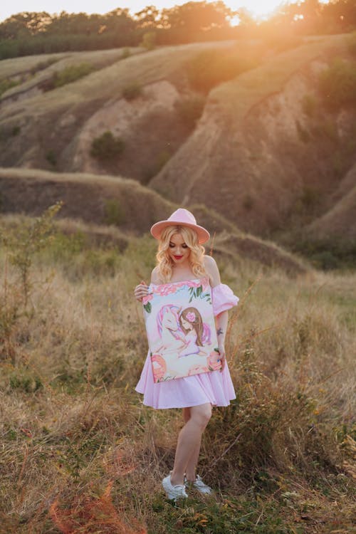 Blonde Woman Standing with Painting at Sunset