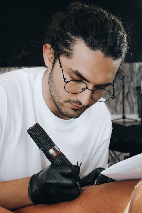 Free Tattoo artist focusing on creating intricate design in a studio setting. Stock Photo