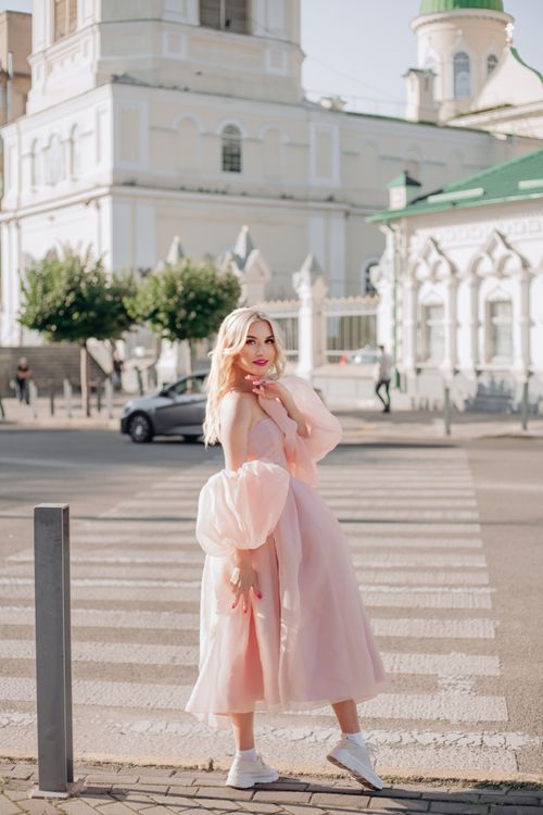 A blonde woman in a pink dress sitting on a bench · Free Stock Photo