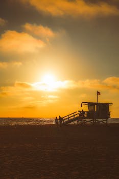 Serene sunset at Santa Monica Beach with silhouette of lifeguard tower and ocean view.