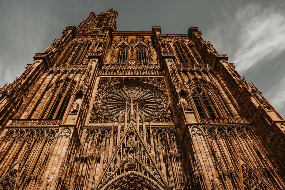 Vue saisissante en contre-plongée de la cathédrale de Strasbourg mettant en valeur ses détails architecturaux gothiques et sa rosace.