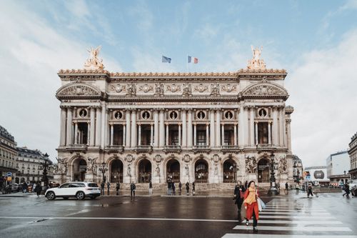 Free Front view of Palais Garnier in Paris with pedestrians crossing and cars passing by. Stock Photo