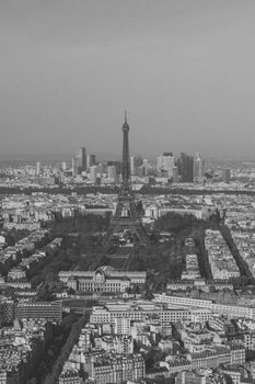Grayscale aerial view of Eiffel Tower surrounded by buildings in Paris cityscape.