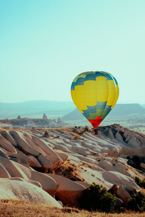 Free Vibrant hot air balloon soaring over the unique rock formations of Cappadocia, Türkiye. Stock Photo