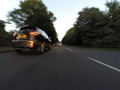 黄昏时，在林荫路上巡航的汽车动作模糊地被捕捉