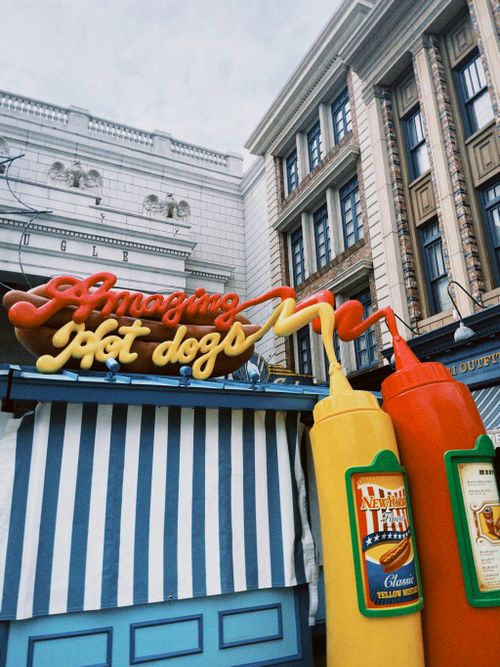 Free Colorful hot dog stand with playful signage and condiment bottles in an urban setting. Stock Photo