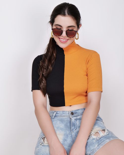Free Smiling woman wearing a stylish bi-color top and denim shorts, exuding summer vibes indoors. Stock Photo
