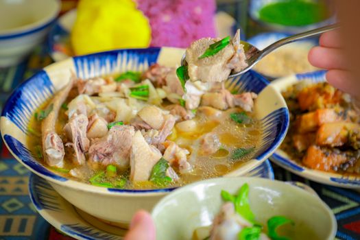 A bowl of soup with meat and vegetables on a plate