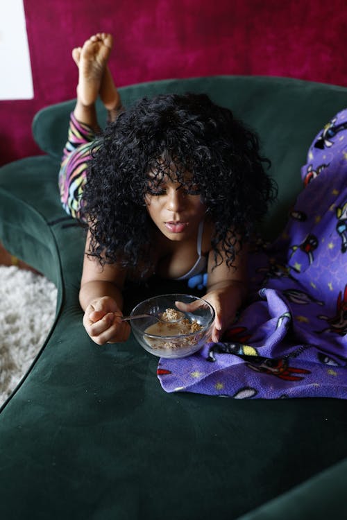 Young Woman Lying on the Sofa and Eating Breakfast