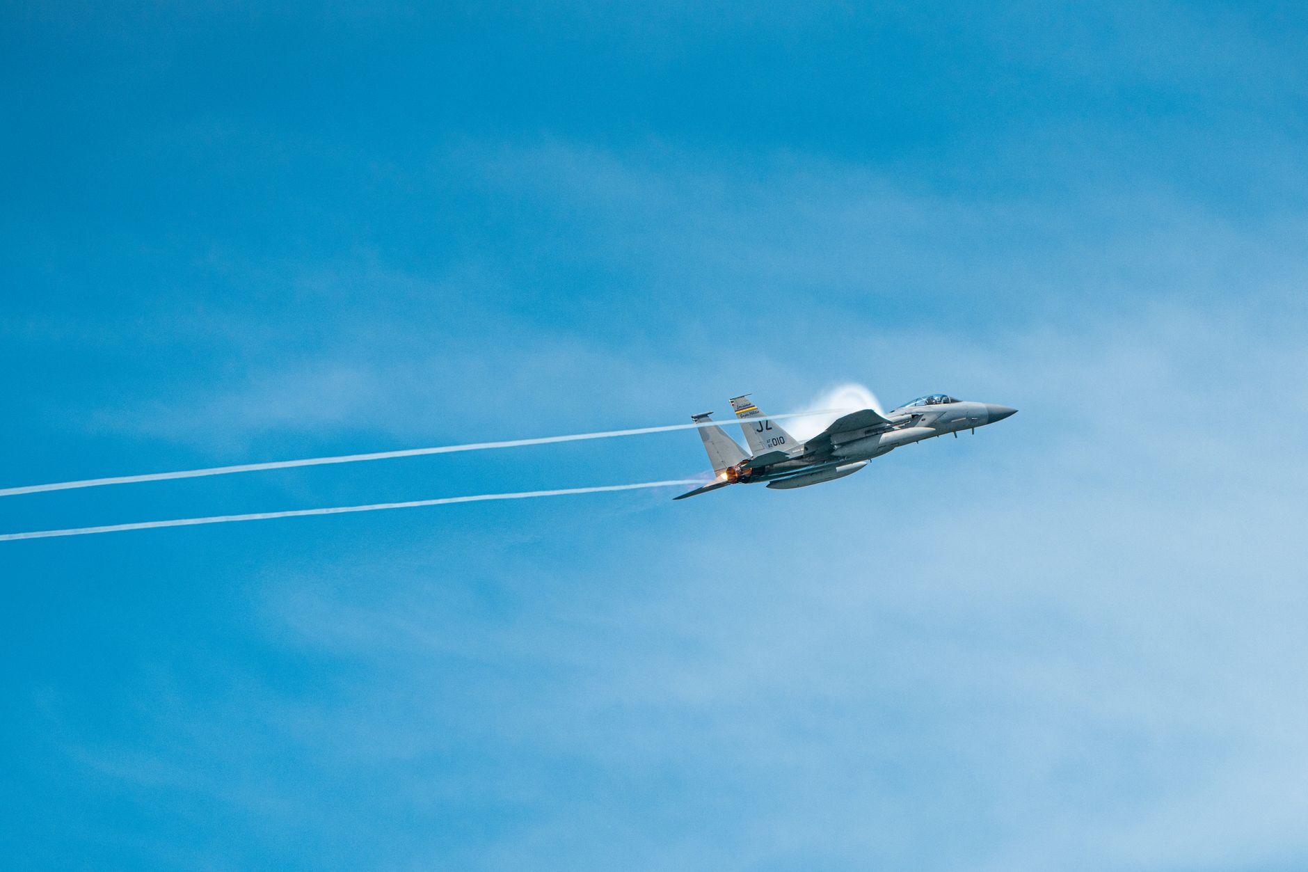 A sleek military jet soaring through a clear blue sky, displaying speed and precision.