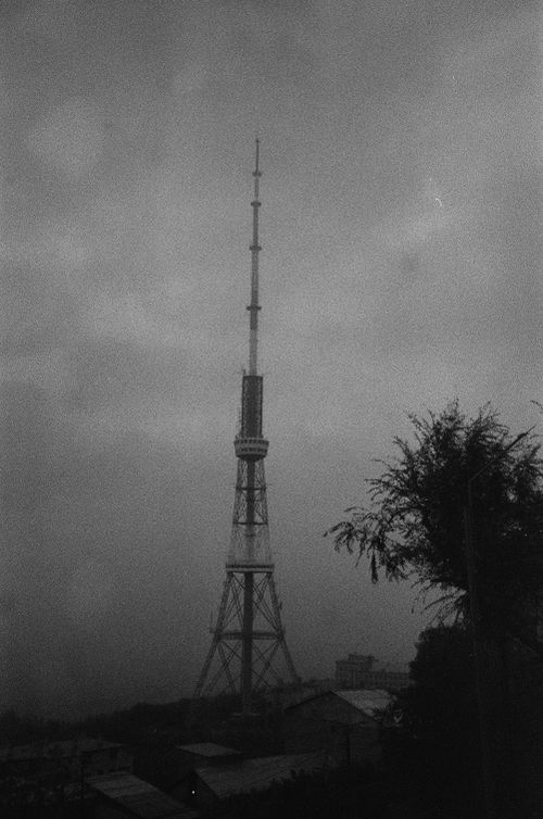 Free Dramatic black and white photo of a tall broadcast tower in a foggy cityscape. Stock Photo