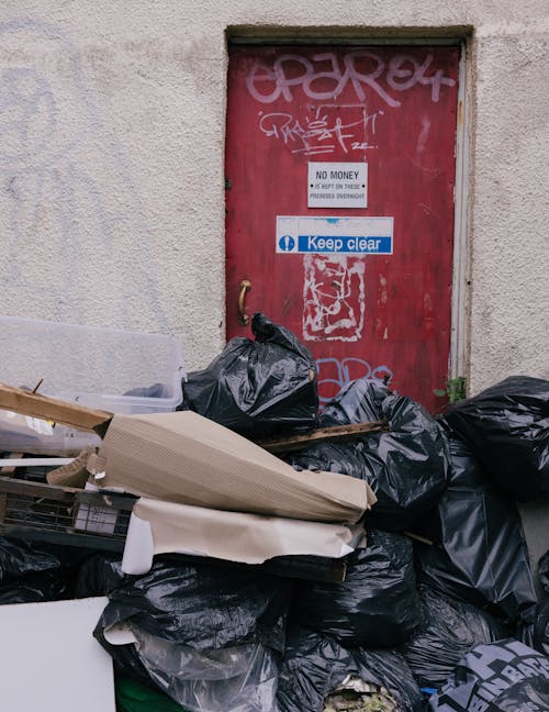 Pile of Garbage Bags and Loose Waste Blocking the Red Door