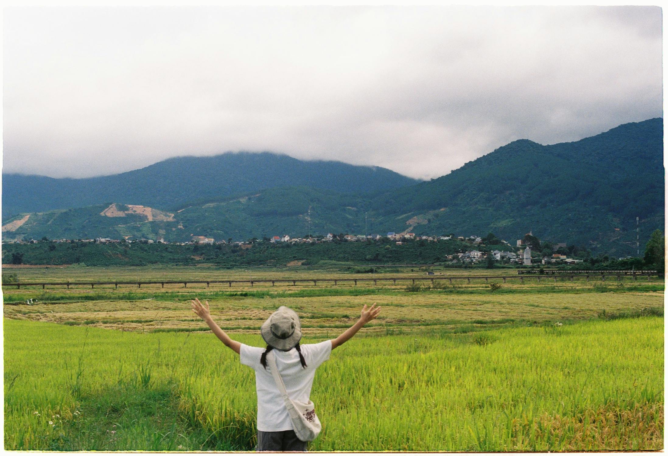 free photo of girl standing in a field with raised arms