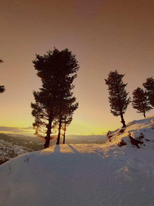 Free Beautiful sunset over snowy hills and trees in Naran, Pakistan, capturing a serene winter landscape. Stock Photo