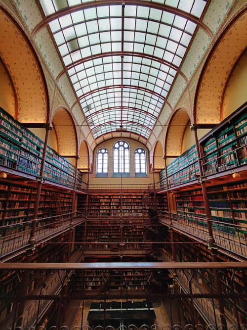 Free Explore the grand interior of a historic library with towering bookshelves and architectural elegance. Stock Photo