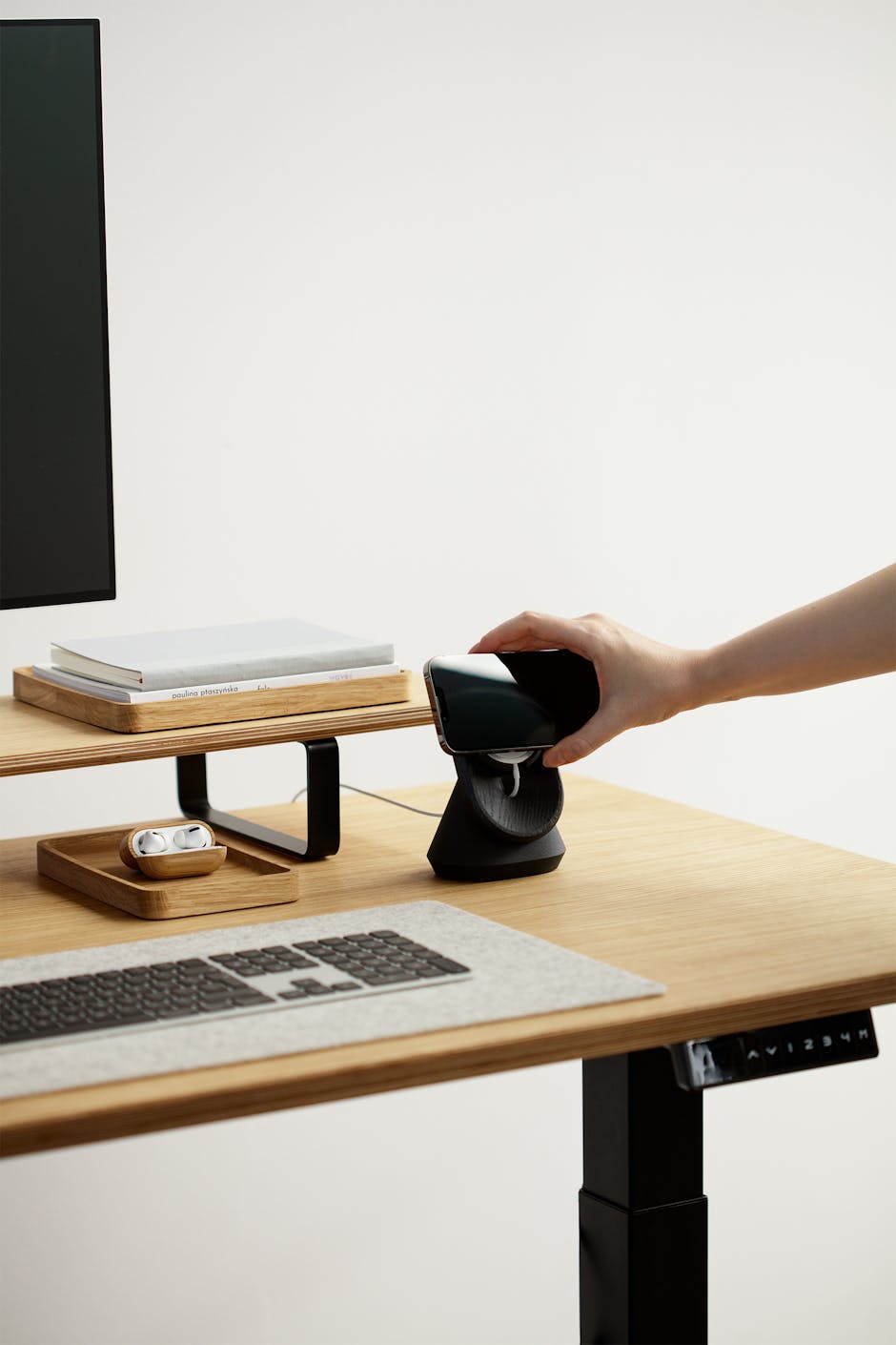 Minimalist workspace featuring a wireless charging station on an adjustable desk.