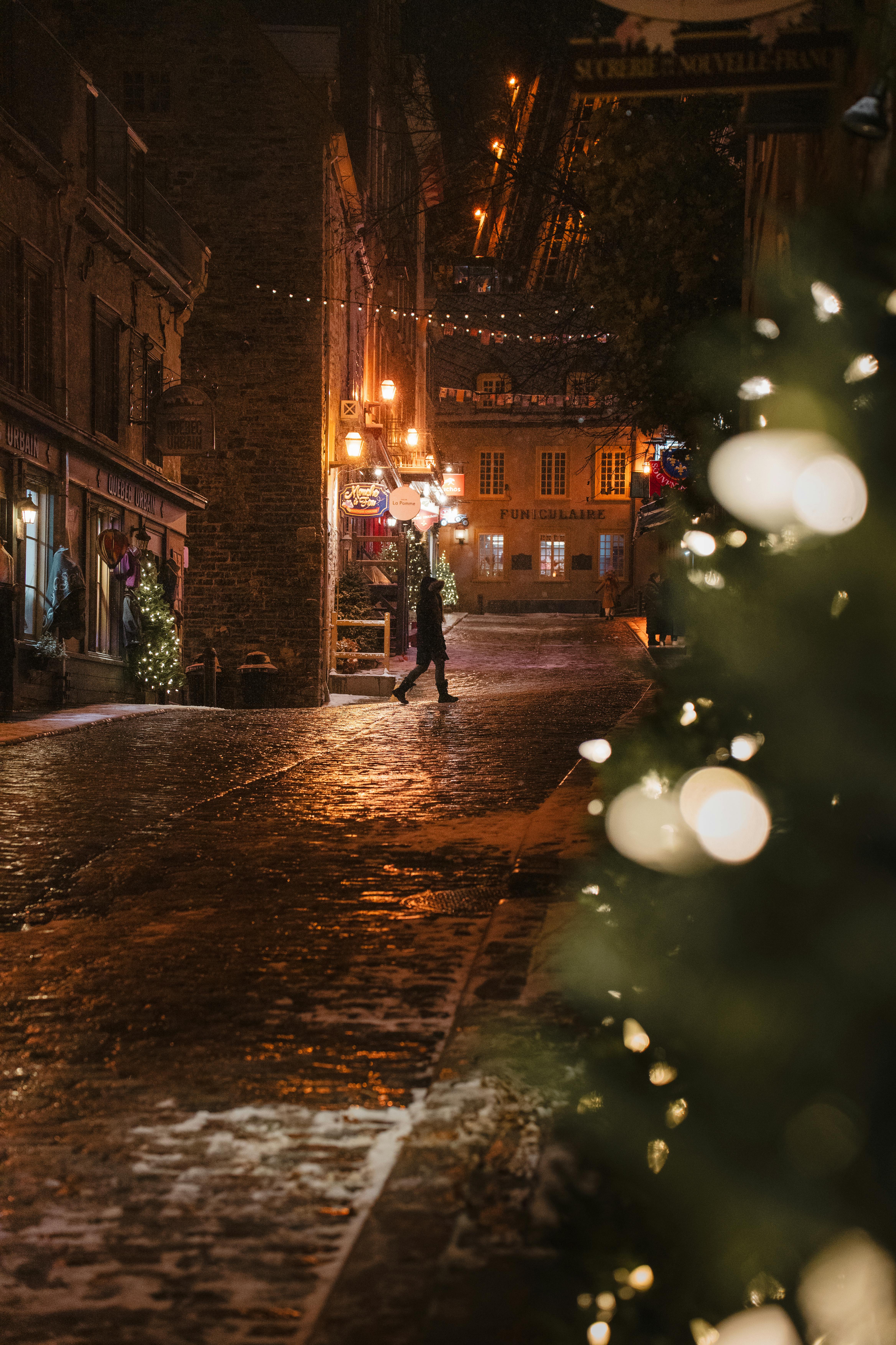 Charming winter evening scene on a cobblestone street in Old Quebec with festive lights.