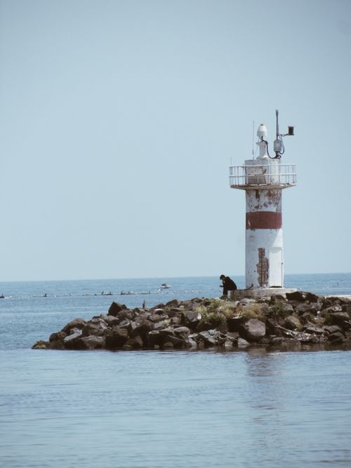Free A lighthouse stands on a rocky shoreline in Marmaraereğlisi, Türkiye, against a calm seascape. Stock Photo