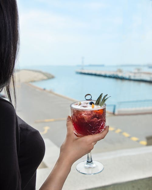 Woman holding cocktail with sea view at restaurant