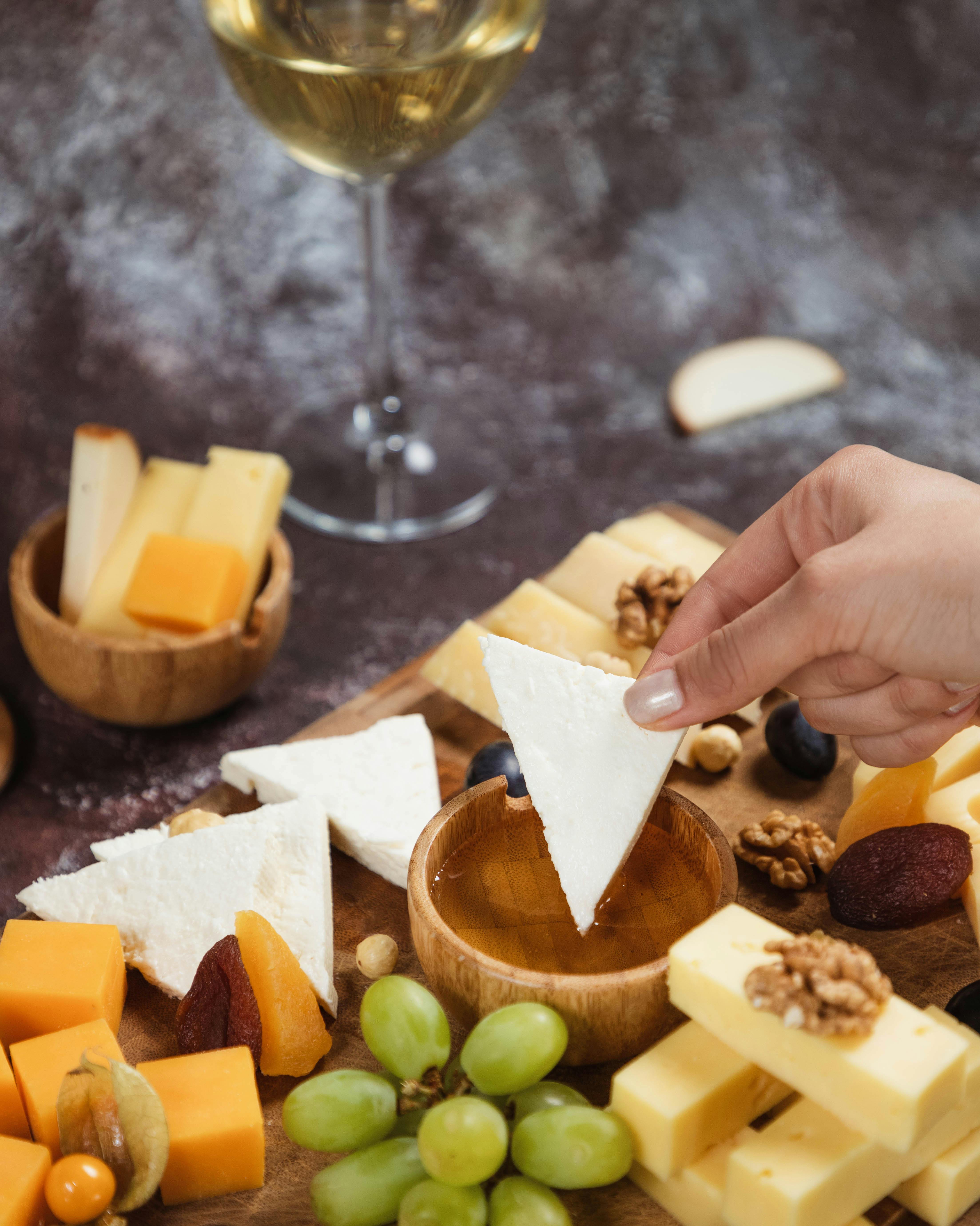 dipping cheese into honey platter snacks and white wine overhead